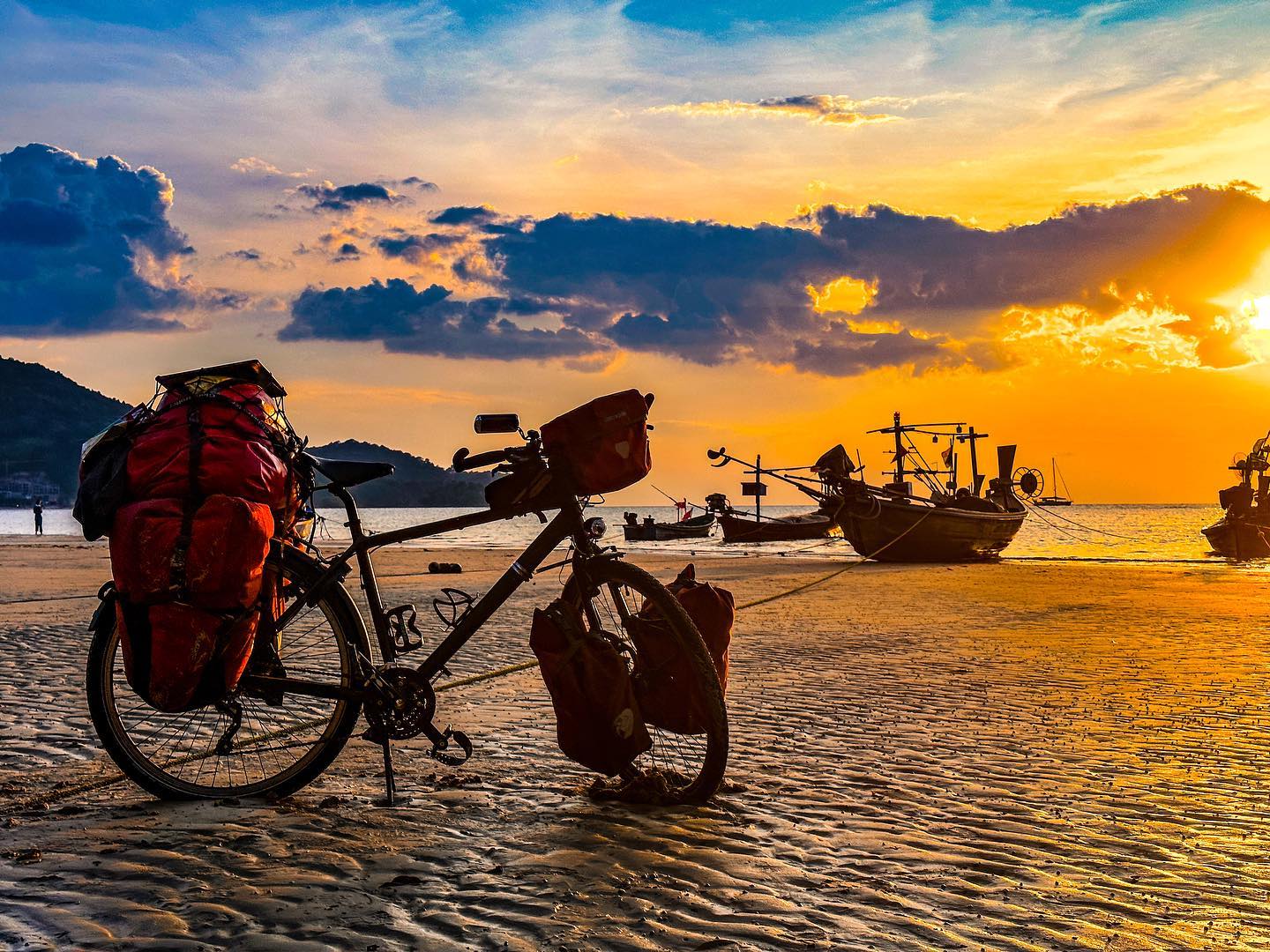 Bicicleta de cicloturismo con alforjas al atardecer en la playa
